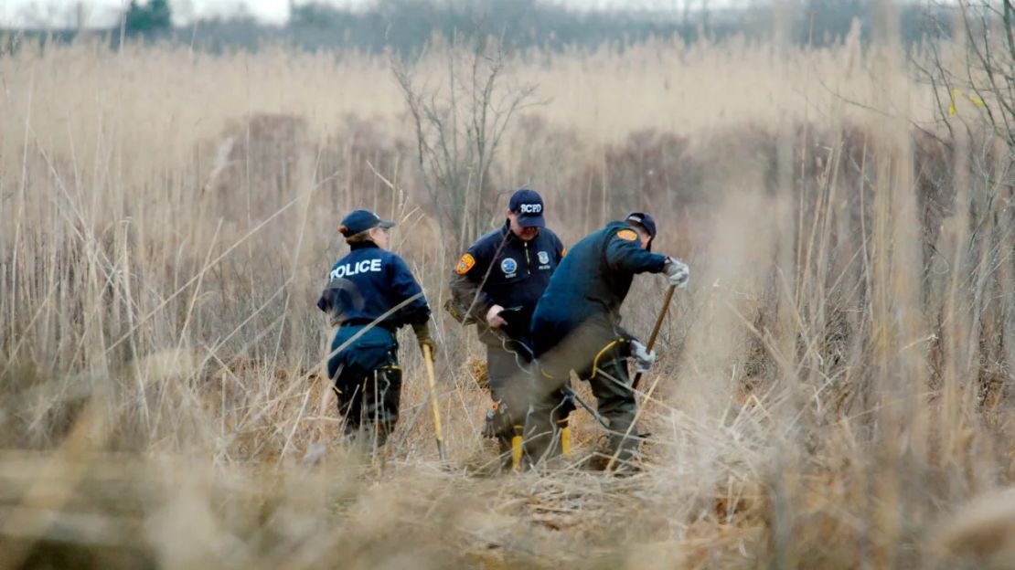 Los investigadores de la escena del crimen usan detectores de metales para buscar restos humanos en un pantano en diciembre de 2011 en Oak Beach, Nueva York.