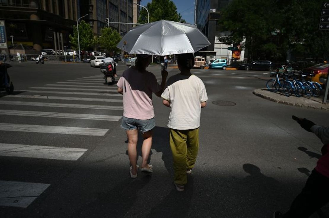 Personas resguardándose del sol mientras cruzan una calle durante una ola de calor en Beijing el 7 de julio de 2023.