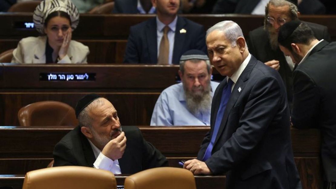 El primer ministro de Israel, Benjamin Netanyahu, habla con Aryeh Deri, presidente del partido ultraortodoxo Shas, durante una sesión del Parlamento en Jerusalén, el 24 de julio de 2023, en medio de una ola de protestas de un mes de duración contra la reforma judicial impulsada por el Gobierno israelí.