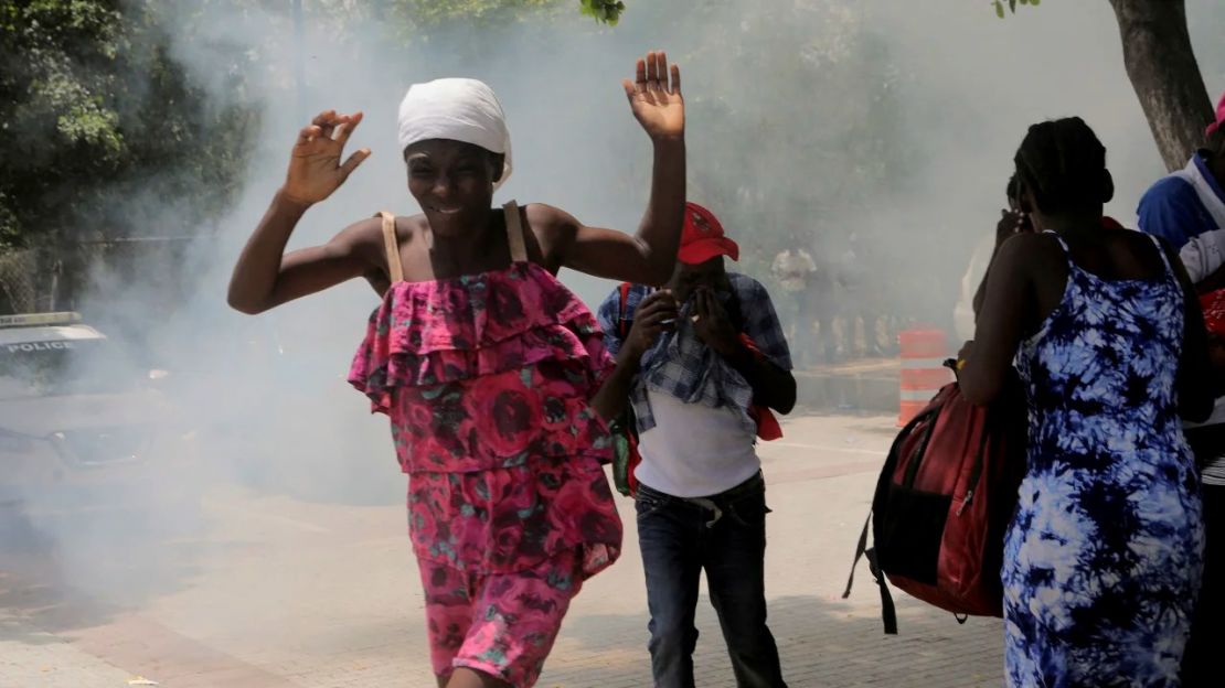 Haitianos huyen de los gases lacrimógenos disparados por los agentes que despejan un campamento de personas en la embajada de EE.UU. que intentan escapar de la violencia de bandas armadas el 25 de julio. Crédito: Ralph Tedy Erol/Reuters