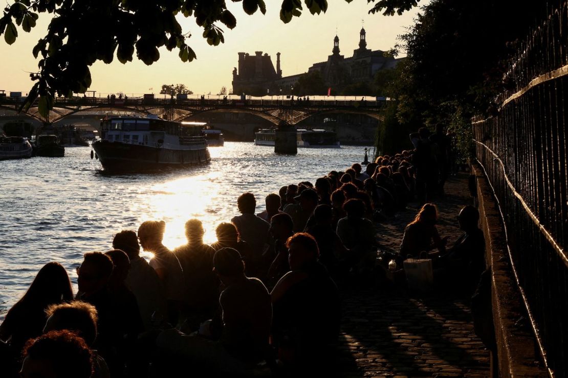 Un grupo de personas disfruta de la puesta de sol en una orilla del río Sena, en París, Francia, en junio.