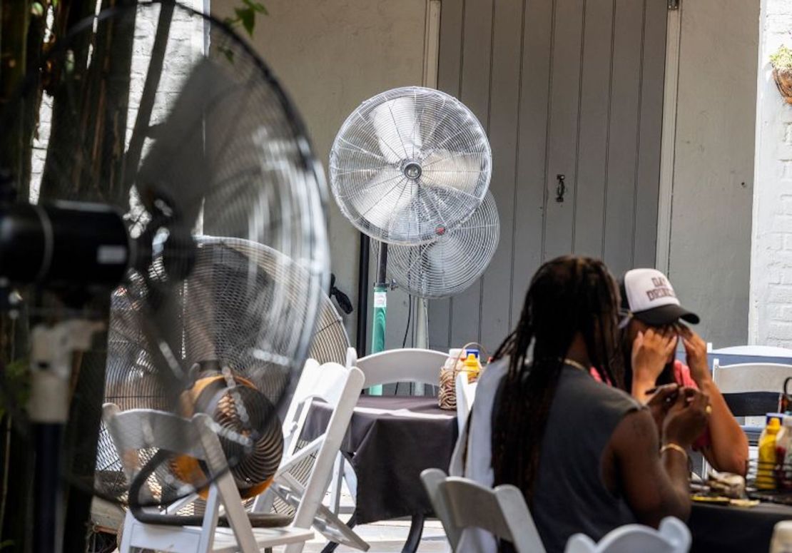 Personas se sientan al lado de un ventilador en medio de una ola de calor récord en el Barrio Francés de Nueva Orleans el lunes 31 de julio de 2023.