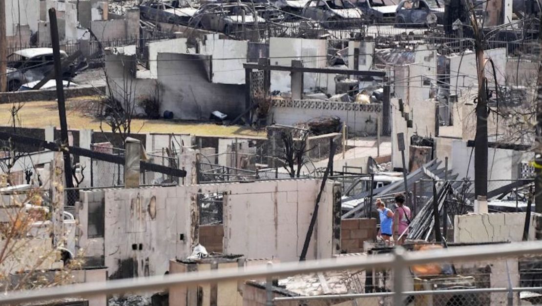 Dos personas examinan el 12 de agosto de 2023 una casa quemada después de que un incendio destruyó gran parte de Lahaina, la histórica ciudad turística de Maui.