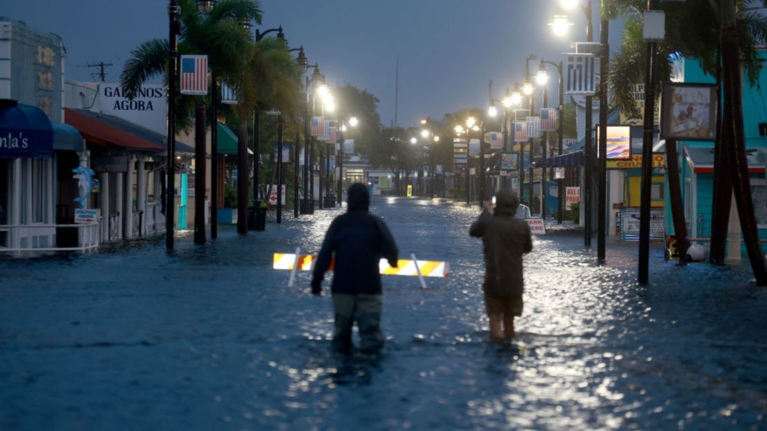 Reporteros caminan a través de las aguas de inundación, que inundan el centro de la ciudad después de que el huracán Idalia pasara mar adentro el 30 de agosto de 2023 en Tarpon Springs, Florida.