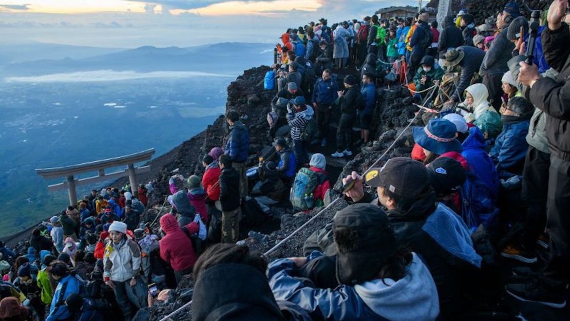 Multitudes de turistas se dirigen a la cima del monte Fuji para contemplar el amanecer.