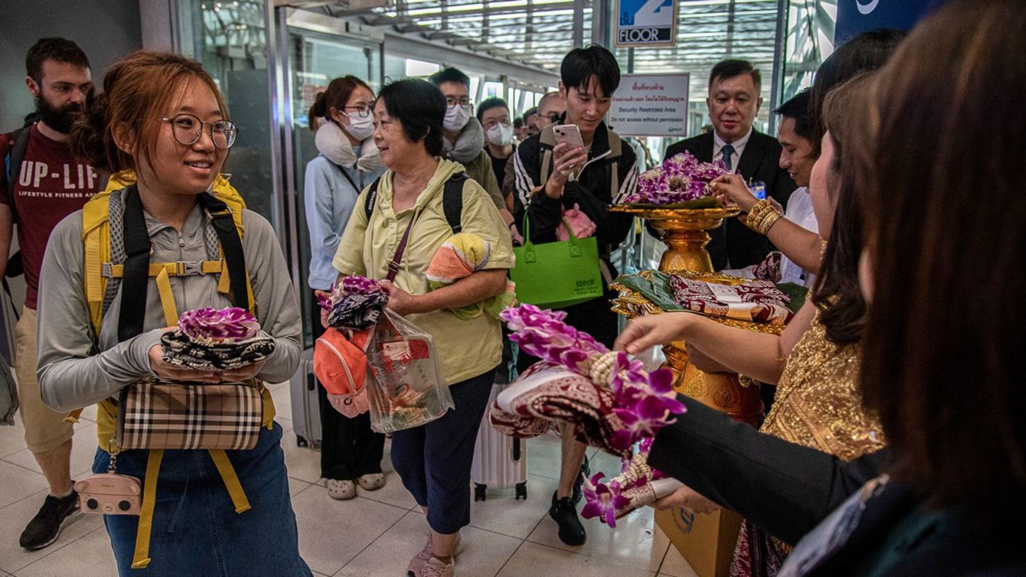 Funcionarios tailandenses reciben a turistas chinos con regalos en el aeropuerto internacional Suvarnabhumi de Bangkok el 25 de septiembre de 2023.