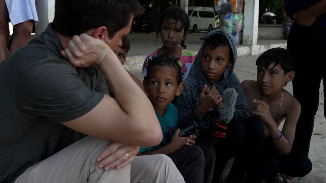 Joandry, de 6 años, en el centro, sostiene el micrófono mientras su hermana Sofía, de 12, y su primo Mathias, de 9, hablan con David Culver, de CNN, en Ciudad Hidalgo, México, a orillas del río Suchiate.