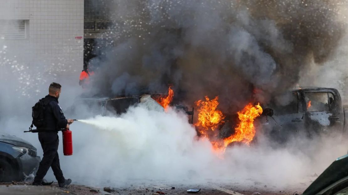 Un miembro de las fuerzas de seguridad israelíes intenta apagar el fuego contra los automóviles tras un ataque con cohetes desde la Franja de Gaza en Ashkelon, en el sur de Israel. Ahmad Gharabli/AFP/Getty Images