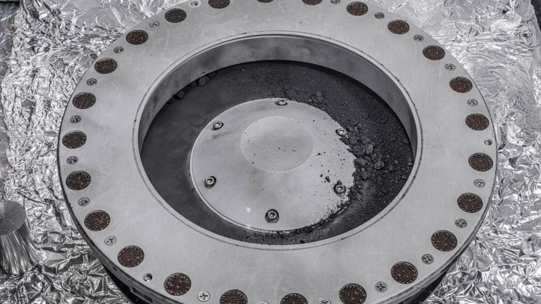 Una vista del exterior del recolector de muestras OSIRIS-REx con material del asteroide Bennu que se puede ver en el centro a la derecha. Los científicos han encontrado evidencia de carbono y agua en el análisis inicial de este material. La mayor parte de la muestra se encuentra en el interior.