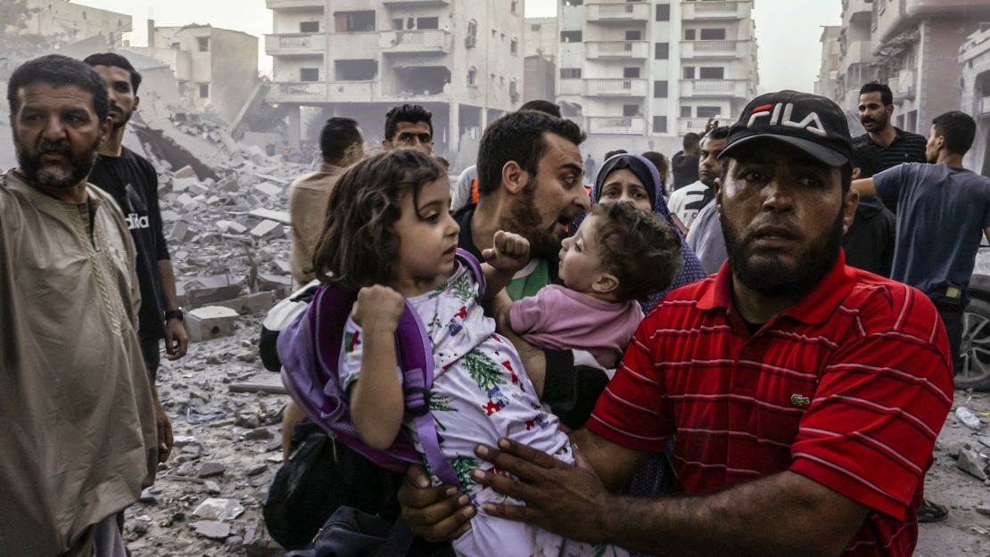 Hombres y mujeres cargan niños en brazos mientras huyen de los ataques de Israel en Rafah, en el sur de Gaza el domingo 15 de octubre de 2023. Crédito: Mohammed Abed/AFP/Getty Images.