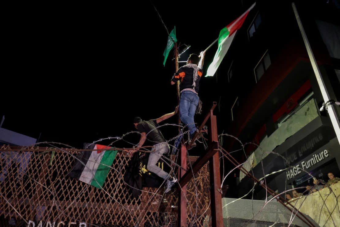 Manifestantes ondean banderas palestinas mientras escalan la valla de la embajada estadounidense en Beirut, Líbano, el 17 de octubre.