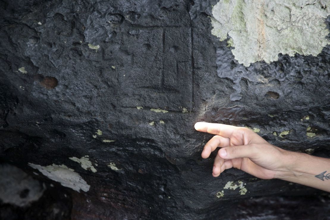 El arqueólogo del Instituto de Medicina y Salud Pública (IPHAM) Jaime de Santana Oliveira señala una antigua talla de piedra.