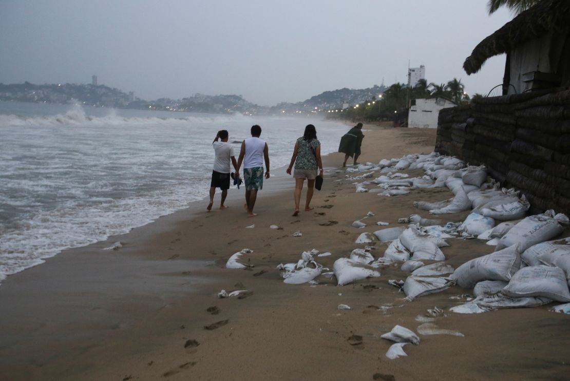 Varias personas caminan por una playa mientras el huracán Otis se dirige hacia Acapulco, México, 24 de octubre de 2023.