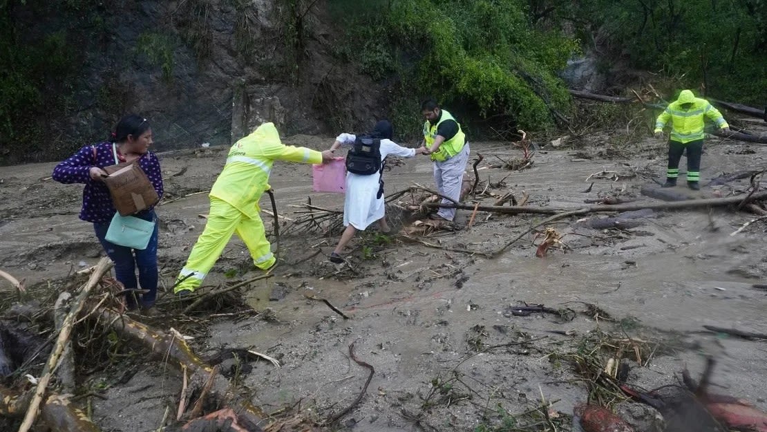 La gente recibe ayuda para cruzar una carretera bloqueada por un deslizamiento de tierra causado por el huracán Otis cerca de Acapulco, México, el miércoles 25 de octubre de 2023. Marco Ugarte/AP