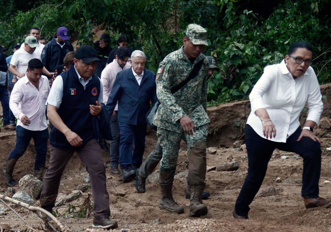 El presidente de México, Andrés Manuel López Obrador, y miembros de su gabinete caminan entre escombros mientras visitan la comunidad Kilómetro 42.