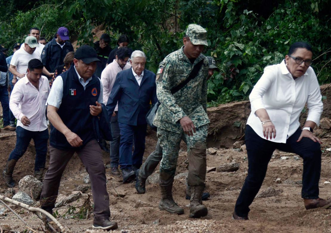 El presidente de México, Andrés Manuel López Obrador, y de su gabinete caminan entre escombros mientras visitan la comunidad Kilómetro 42.