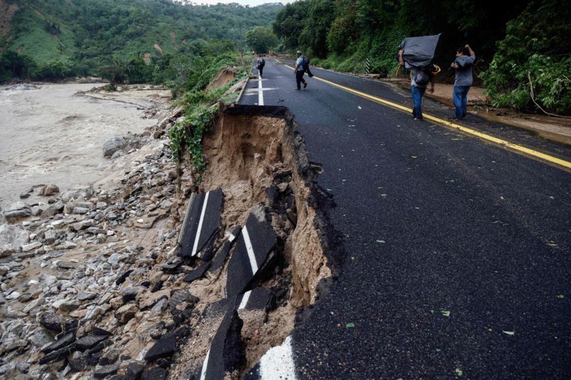 Personas pasan junto a parte de una carretera que fue arrasada por las aguas cerca de Acapulco, estado de Guerrero, México, tras el paso del huracán Otis, el 25 de octubre de 2023.