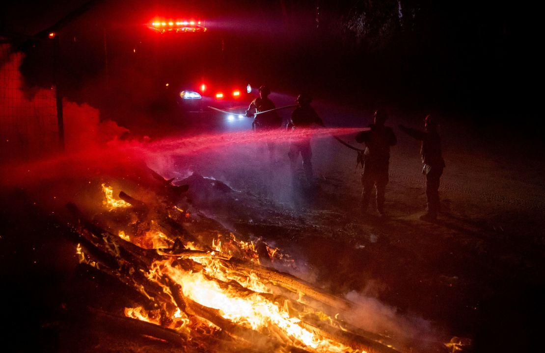 Los bomberos apagan las llamas mientras luchan contra el incendio forestal Highland en Aguanga, California, el lunes 30 de octubre. Crédito: Ethan Swope/AP