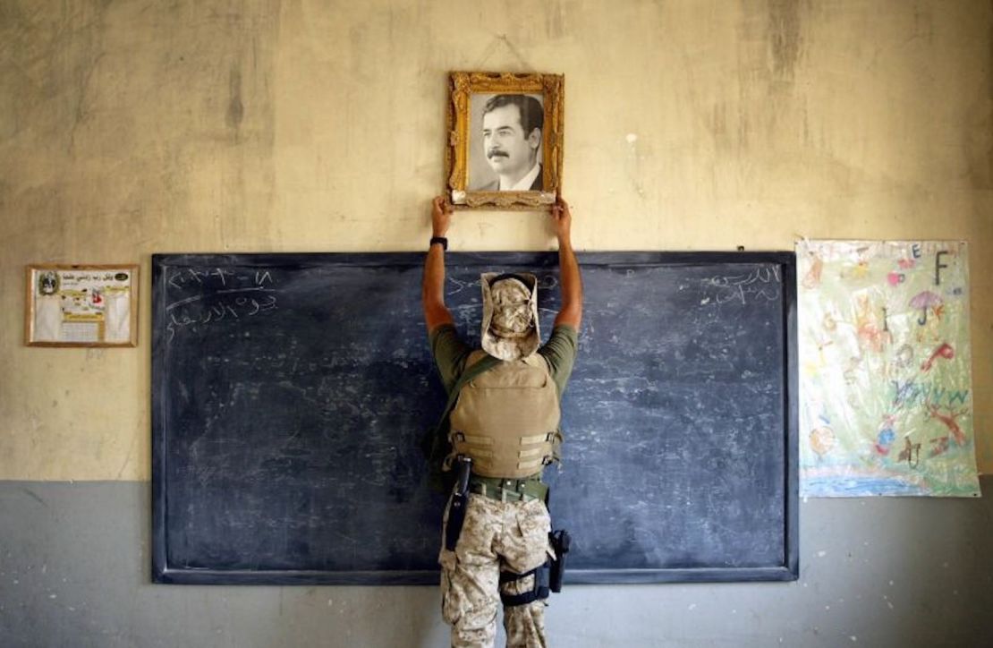 Un infante de Marina estadounidense retira una foto de Saddam Hussein de una escuela de Al-Kut, Iraq, en 2003.