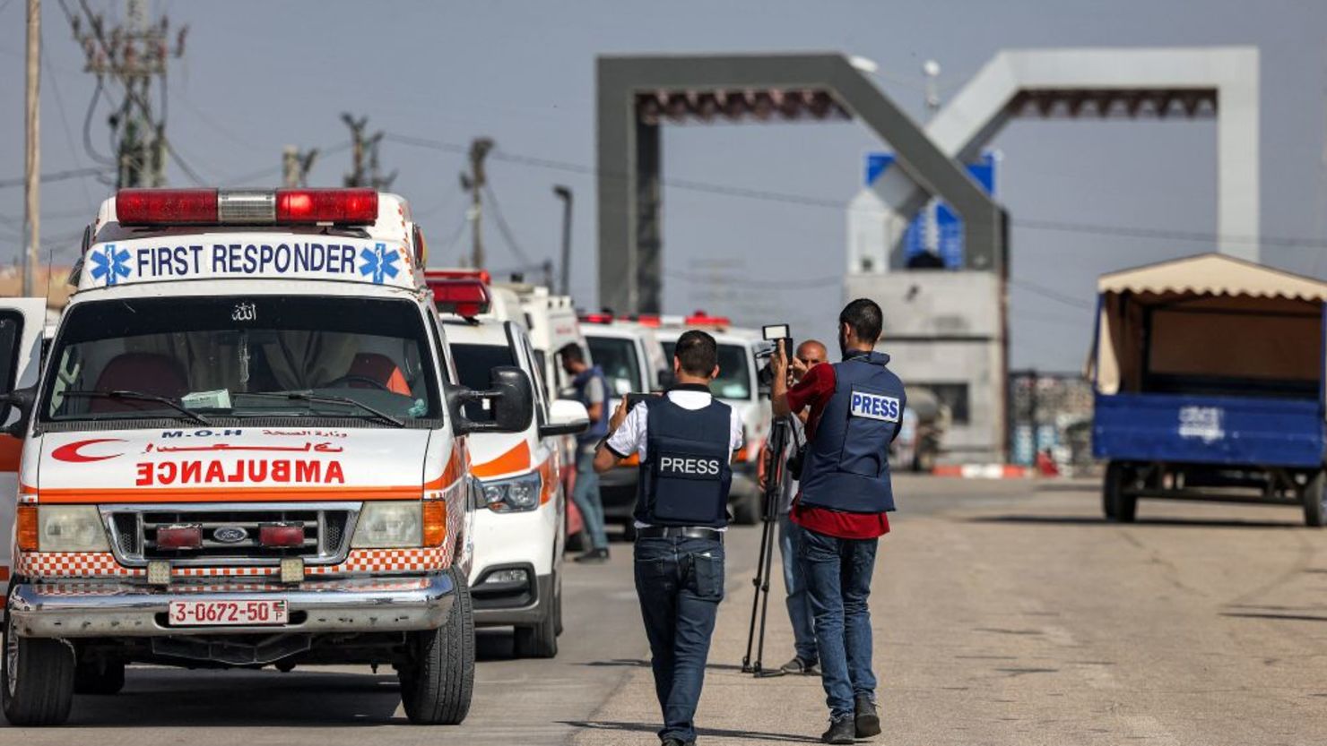 Periodistas filman cómo ambulancias del Ministerio de Sanidad palestino cruzan la puerta para entrar en el paso fronterizo de Rafah, en el sur de la Franja de Gaza, antes de cruzar a Egipto, el 1 de noviembre de 2023. Decenas de titulares de pasaportes extranjeros atrapados en Gaza comenzaron a abandonar el territorio palestino devastado por la guerra el 1 de noviembre, cuando se abrió el paso fronterizo de Rafah a Egipto por primera vez desde los ataques del 7 de octubre de Hamás contra Israel, según corresponsales de AFP.