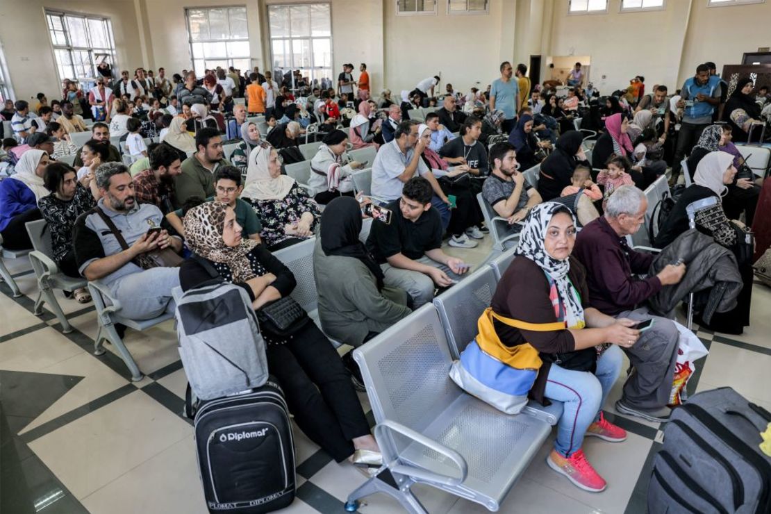 Varias personas sentadas en la zona de espera del paso fronterizo de Rafah, en el sur de Gaza, antes de cruzar a Egipto, el 1 de noviembre de 2023.