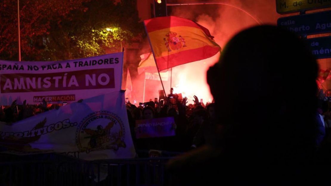 Manifestantes sostienen banderas y pancartas españolas durante una protesta convocada por movimientos de extrema derecha contra las negociaciones gubernamentales para conceder una amnistía a las personas involucradas en el fallido intento de independencia de Cataluña de 2017, cerca de la sede del Partido Socialista Obrero Español (PSOE) en Madrid, el 7 de noviembre de 2023.