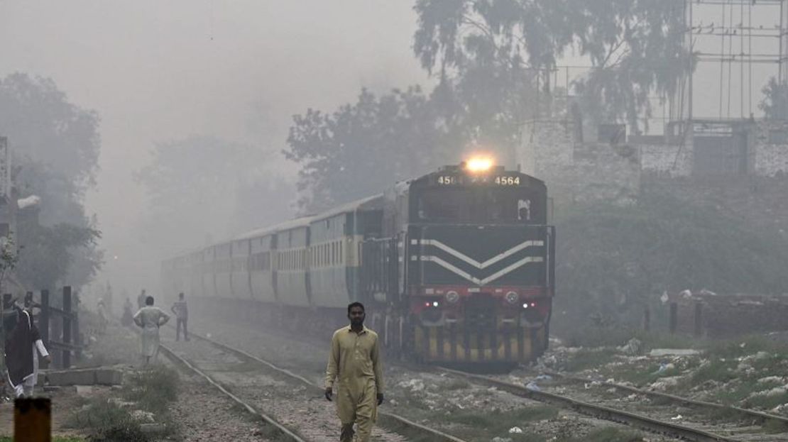 Viajeros recorren las vías del tren en medio de la niebla tóxica en Lahore el 7 de noviembre de 2023.