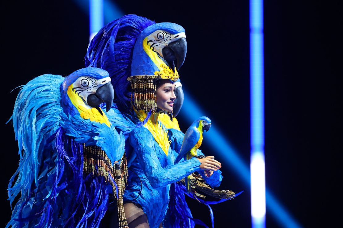 Un trío de loros guacamayos azules se posó sobre los hombros, literalmente, de Miss Brasil, cuyo traje típico buscó resaltar que la especie está amenazada.