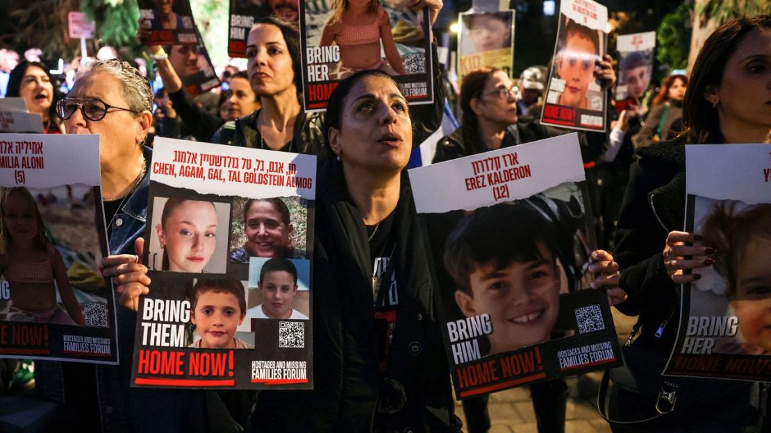 Una mujer sostiene retratos de los rehenes Erez Kalderon, de 12 años, y de los niños de la familia Goldstein Almog, mientras manifestantes se concentran frente a las oficinas de la Unicef en Tel Aviv el 20 de noviembre de 2023 para exigir la liberación de los israelíes tomados como rehenes.