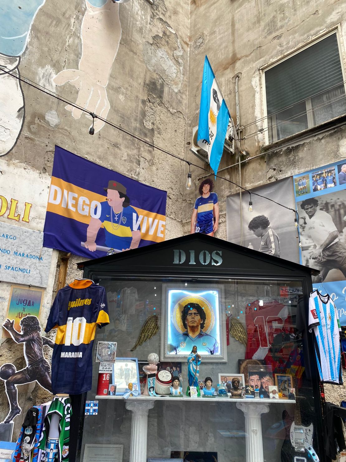 Un altar con imágenes, bustos y banderas a los pies del gran mural de los Quartieri Spagnoli.