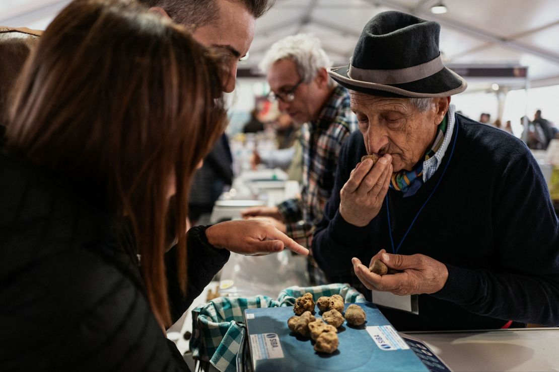 Un vendedor huele trufas blancas en una feria de trufas en el noroeste de Italia.