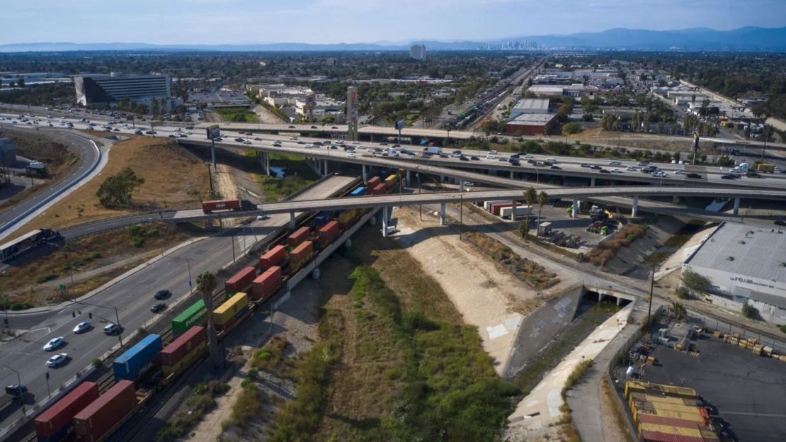 Una larga fila de contenedores de carga pasa bajo una carretera en Compton, California, EE.UU., el martes 2 de agosto de 2022.