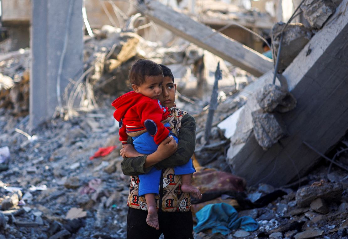 Un niño palestino con un bebé se encuentra en el lugar de los ataques israelíes en Rafah, en el sur de Gaza, el 4 de diciembre. Mohammed Salem/Reuters