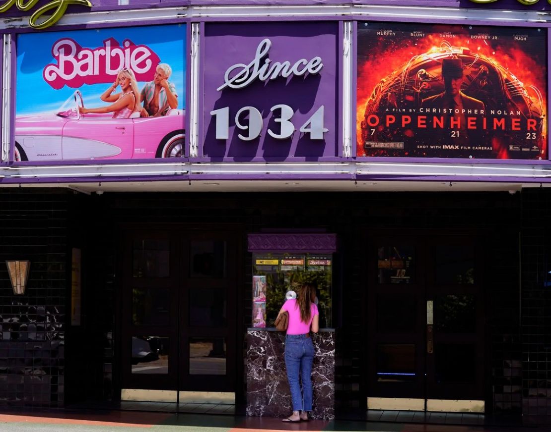 Una cliente compra una entrada de cine bajo una marquesina con las películas "Barbie" y "Oppenheimer" en el Teatro Los Feliz, el viernes 28 de julio de 2023, en Los Ángeles.