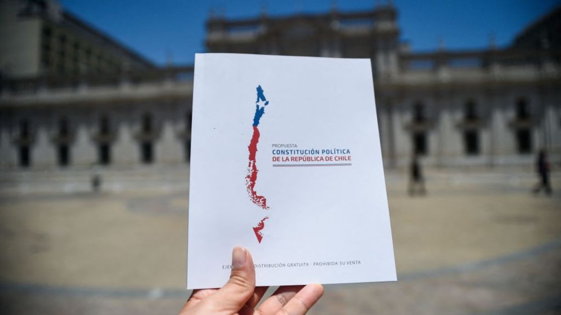 Un hombre sostiene una copia de la nueva Constitución propuesta para Chile frente al Palacio Presidencial de La Moneda, en Santiago, el 12 de diciembre de 2023.