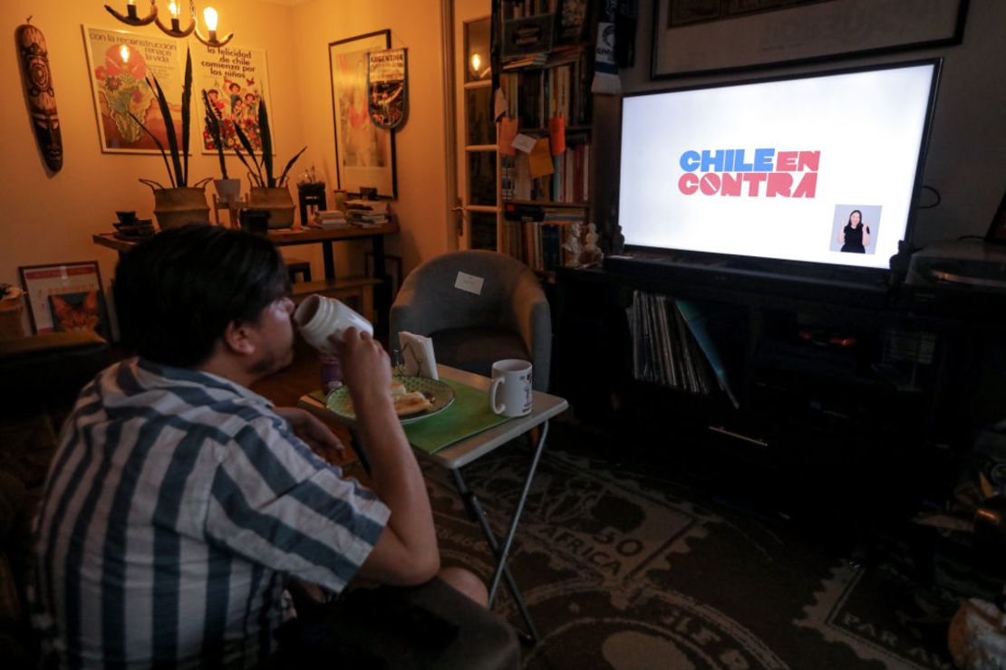 Una persona mira la televisión donde puede verse un video de la campaña "en contra" de cara al plebiscito de este domingo en Chila.