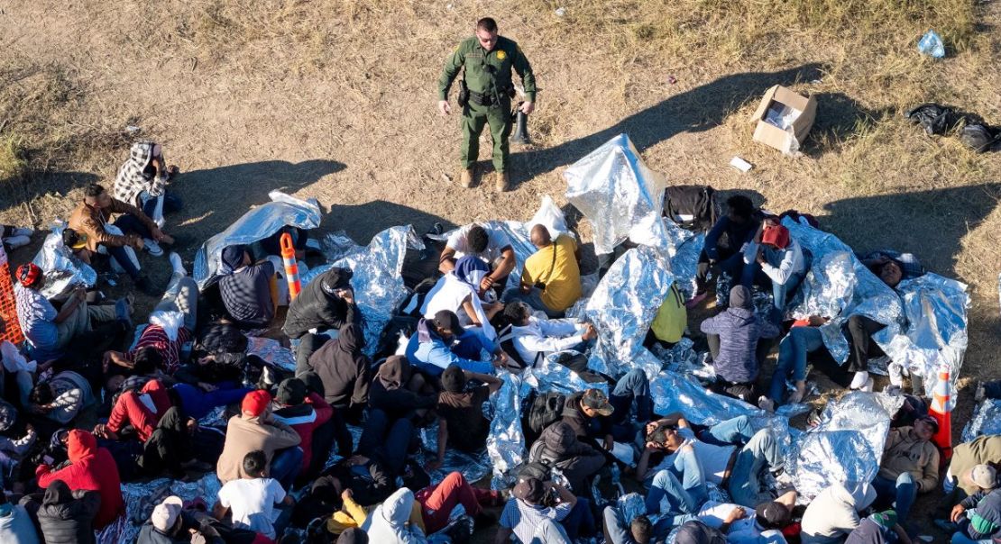 Un agente de la Patrulla Fronteriza de Estados Unidos habla con migrantes que esperan ser procesados después de cruzar de México a Estados Unidos el 17 de diciembre en Eagle Pass, Texas.