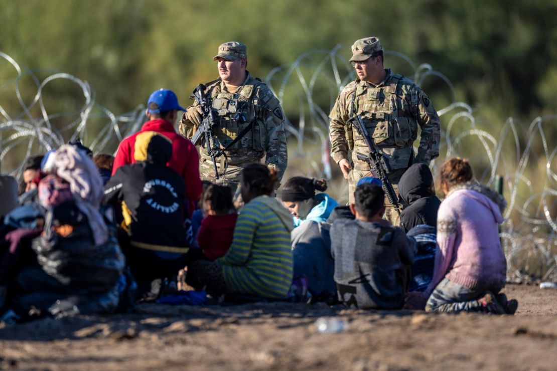 Tropas de la Guardia Nacional de Texas vigilan a algunos de los más de 1.000 inmigrantes que cruzaron el Río Grande desde México el 18 de diciembre de 2023 en Eagle , Texas.