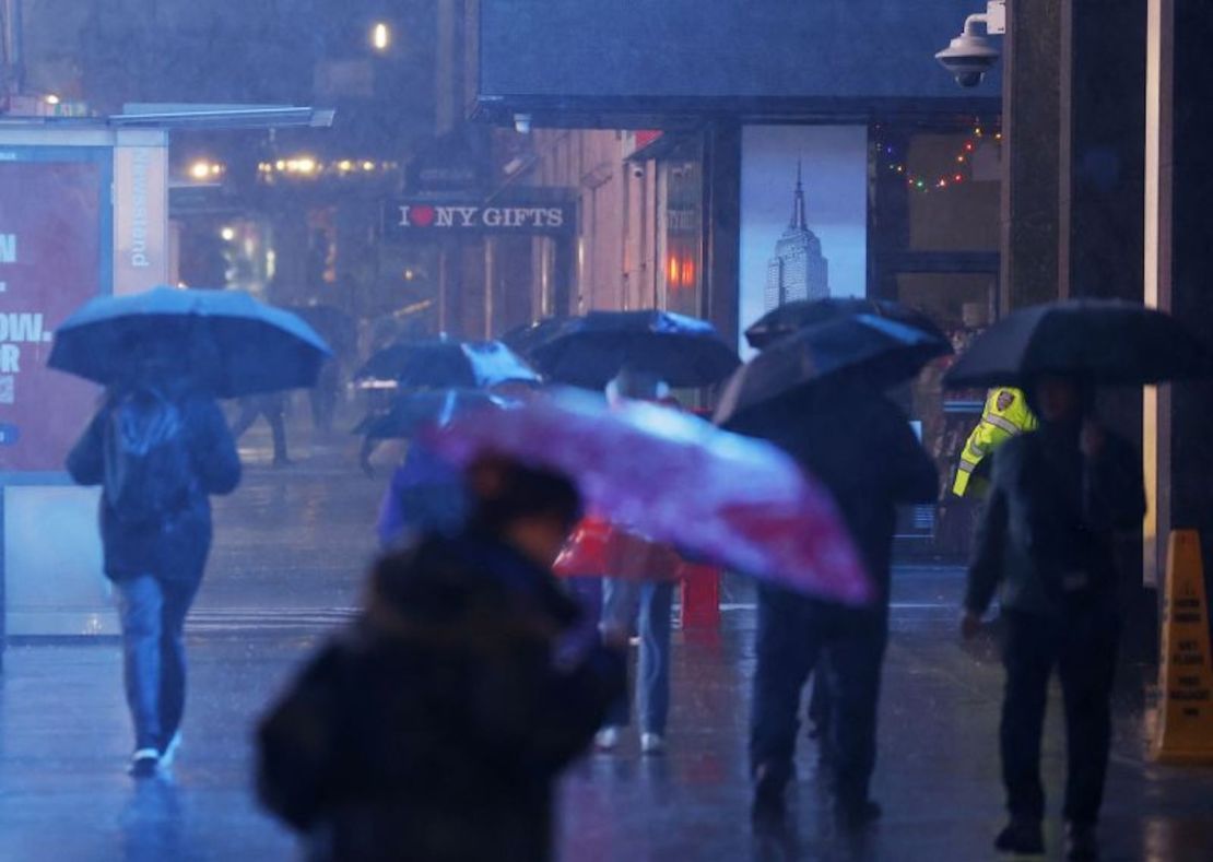 Peatones cargan paraguas mientras caminan bajo una fuerte lluvia en Times Square en la ciudad de Nueva York el lunes 18 de diciembre de 2023.