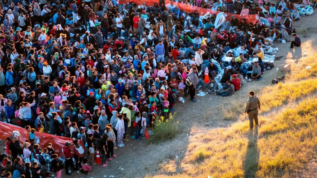 En una vista aérea, un agente de la Patrulla Fronteriza estadounidense vigila a los migrantes que esperan a ser procesados tras cruzar de México a Estados Unidos el 17 de diciembre de 2023 en Eagle , Texas. La oleada de migrantes, hasta 12.000 al día, que cruzan la frontera sur de Estados Unidos ha desbordado a las autoridades de inmigración estadounidenses. Crédito: John Moore/Getty Images