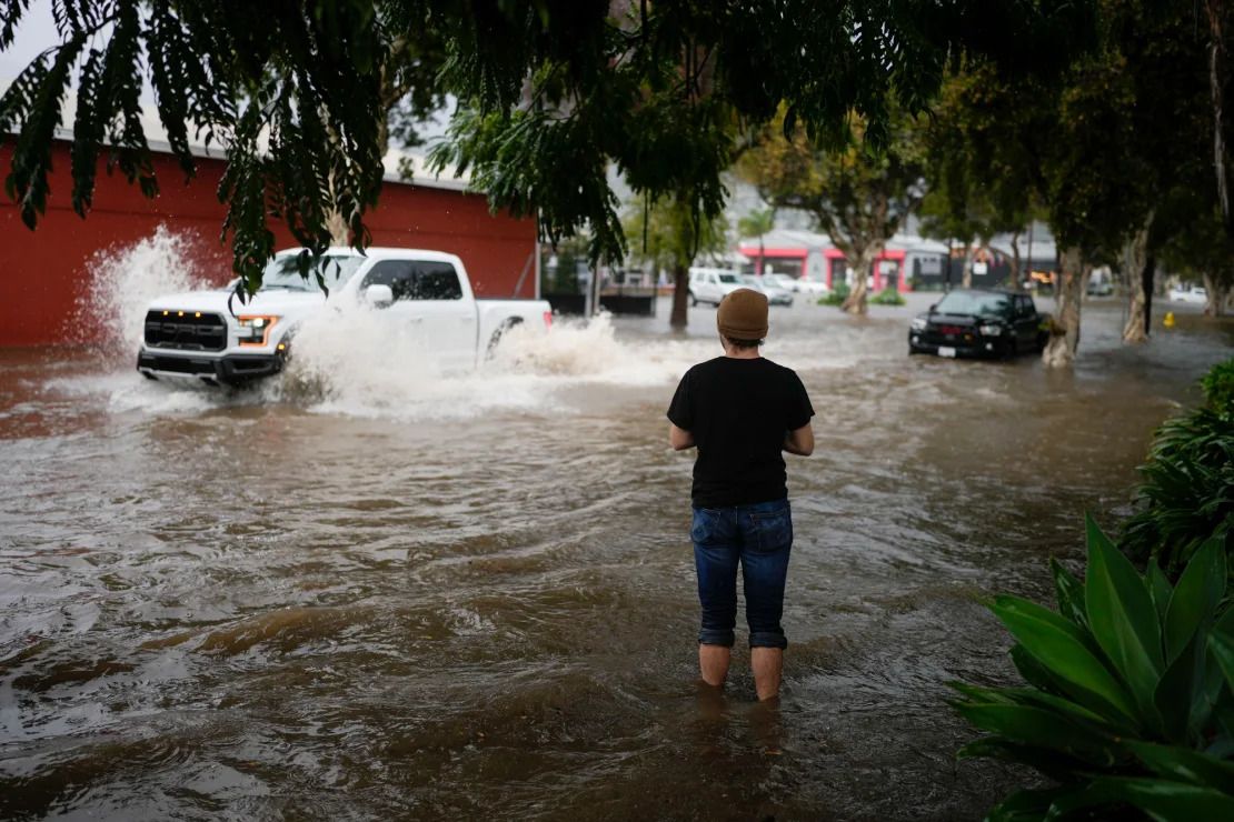 Un hombre observa a los automovilistas conducir por una calle inundada durante una tormenta el jueves en Santa Bárbara, California.