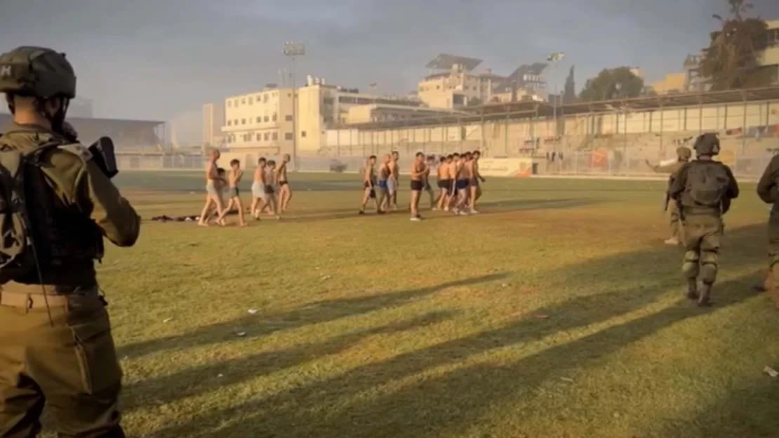 Una captura de imagen del video parece mostrar a mujeres y hombres palestinos con los ojos vendados y las manos atadas a la espalda mientras están sentados en el césped frente a una portería de fútbol en el estadio.