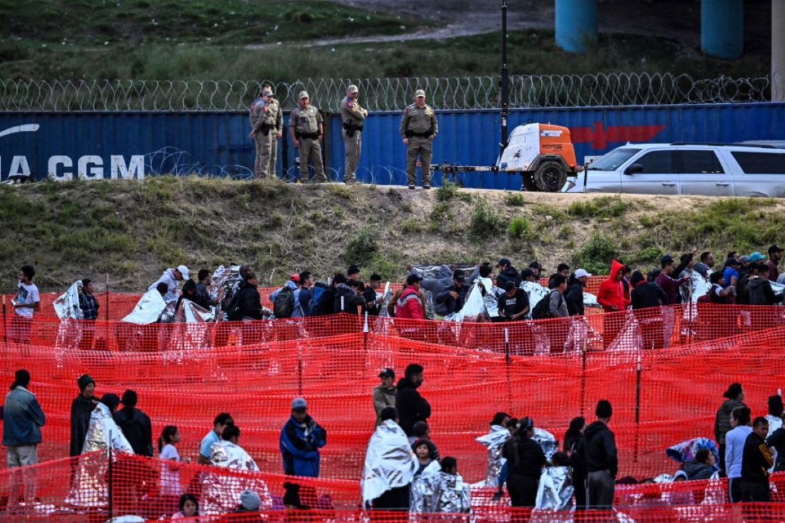 Agentes de Aduanas y Protección Fronteriza hacen guardia mientras los inmigrantes esperan ser procesados en un centro de tránsito de la Patrulla Fronteriza de EE.UU. después de cruzar la frontera desde México en Eagle Pass, Texas, el 22 de diciembre de 2023. Crédito: CHANDAN KHANNA/AFP vía Getty Images