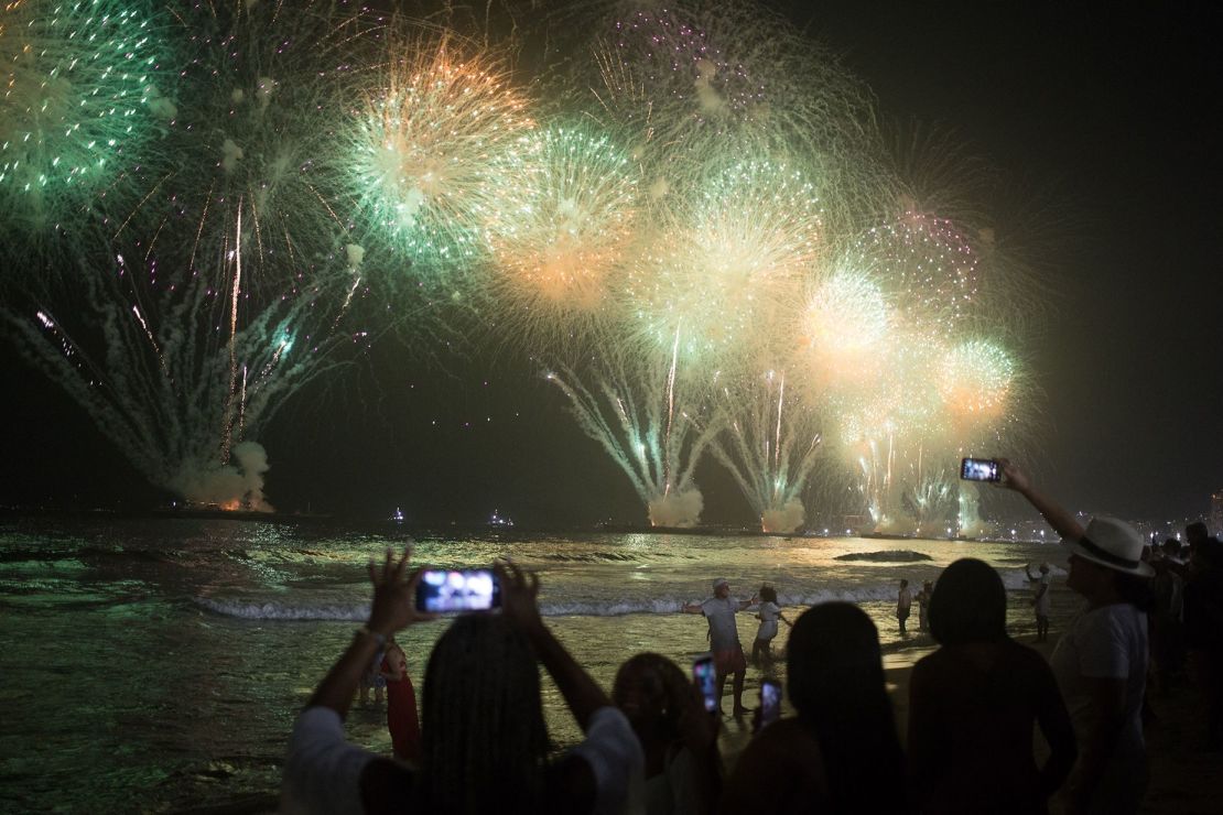 La gente celebra mientras los tradicionales fuegos artificiales de Año Nuevo iluminan el cielo en la playa de Copacabana en Río de Janeiro el 1 de enero de 2023. Crédito: Pedro Prado/AFP/Getty Images