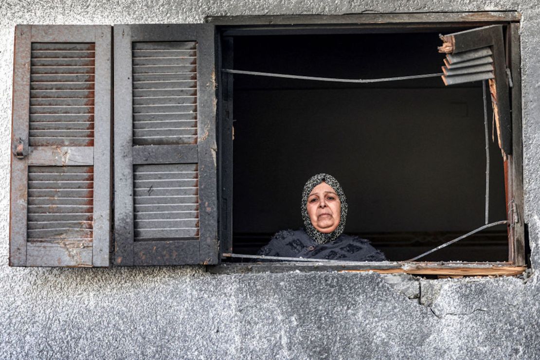 Una mujer mira por la ventana de una casa frente al edificio donde se refugiaba la familia palestina desplazada Jabalieh tras ser alcanzado por un bombardeo israelí en Rafah, en el sur de Gaza, el 3 de enero de 2024, en medio del conflicto en curso entre Israel y el grupo extremista palestino Hamas.