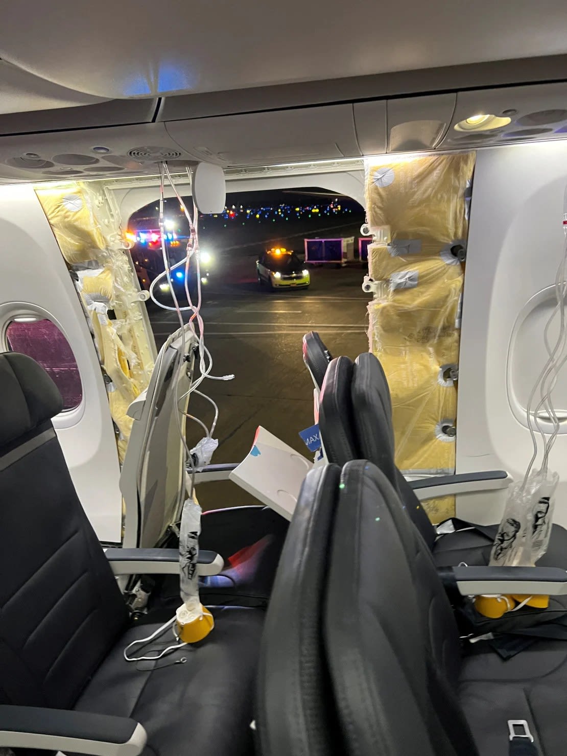 Las máscaras de oxígeno de los pasajeros cuelgan del techo junto a una ventana faltante y una parte de una pared lateral de un vuelo 1282 de Alaska Airlines.