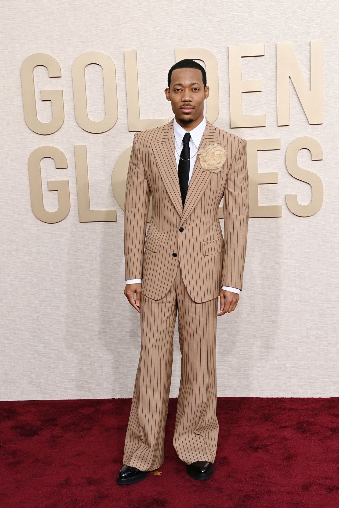 La estrella de "Abbott Elementary", Tyler James Williams, lució un traje de Dolce & Gabbana de raya diplomática y pierna ancha, complementado con un broche de rosetón y un collar de David Yurman.