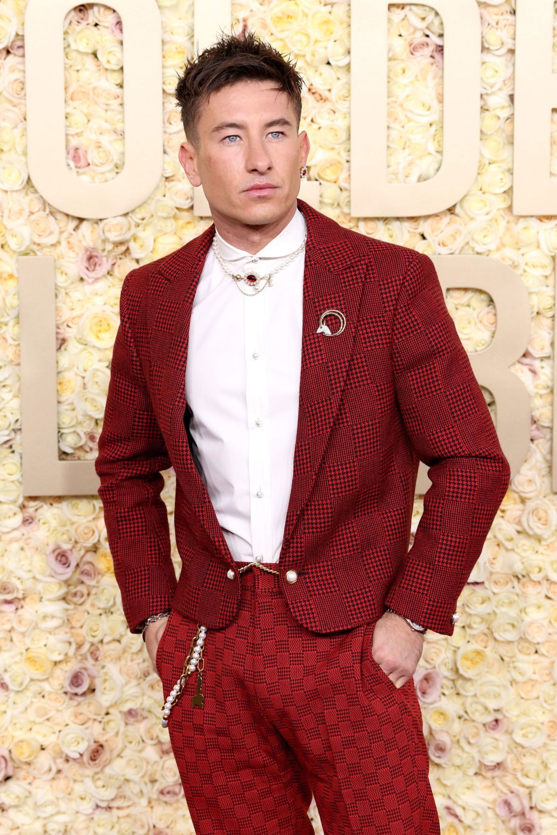 Barry Keoghan lució una chaqueta de noche de lana roja con el característico estampado Damier de Louis Vuitton. Completó el look con unos pantalones rojos a cuadros de la colección Primavera-Verano 2024 de la firma, un cinturón de perlas, un collar, unos pendientes y un broche de Tiffany & Co.