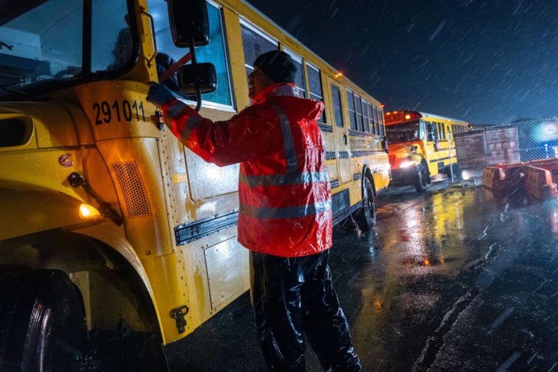 Migrantes son evacuados en autobuses escolares desde las tiendas de campaña en Floyd Bennett Field a una escuela secundaria local en preparación para una tormenta el martes en Brooklyn.