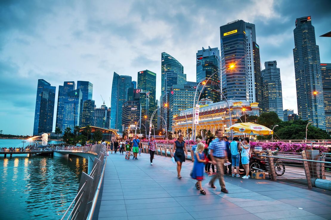 Singapur es caro y caluroso, pero ofrece excelentes perspectivas laborales y gastronómicas. Aquí la gente da un paseo por la bahía del puerto deportivo.